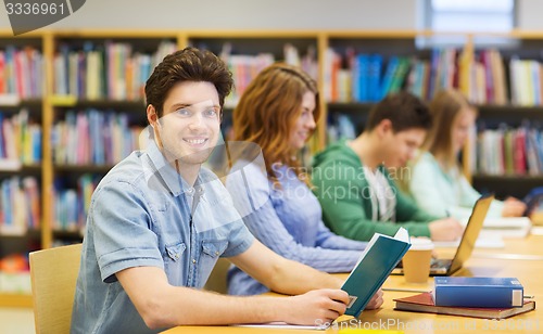 Image of happy student boy reading books in library