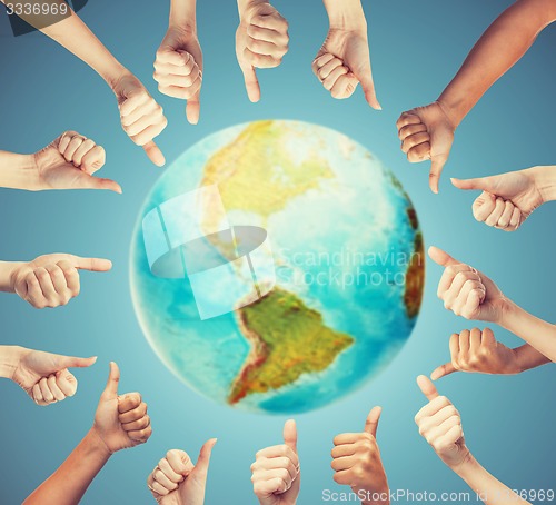 Image of human hands showing thumbs up in circle over earth