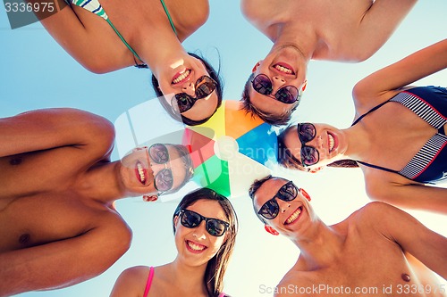 Image of smiling friends in circle on summer beach