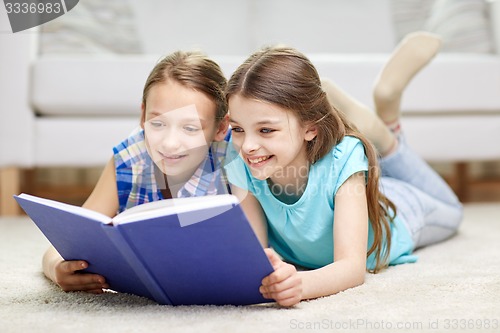 Image of two happy girls reading book at home