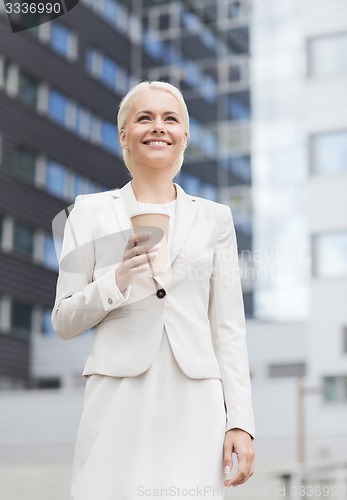 Image of smiling businesswoman with paper cup outdoors