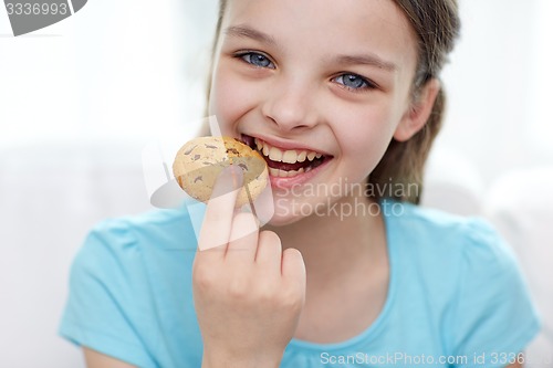Image of smiling little girl eating cookie or biscuit