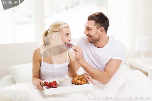 Image of happy couple having breakfast in bed at home