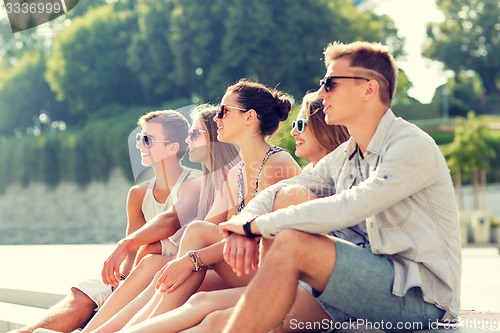 Image of group of smiling friends sitting on city square