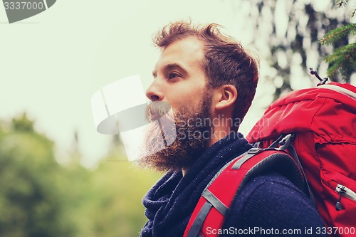 Image of smiling man with beard and backpack hiking