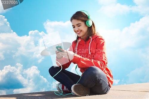 Image of happy young woman with smartphone and headphones