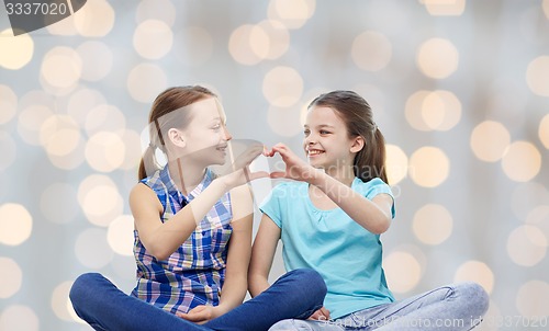 Image of happy little girls showing heart shape hand sign