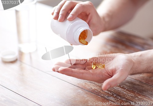 Image of close up of man pouring fish oil capsules to hand