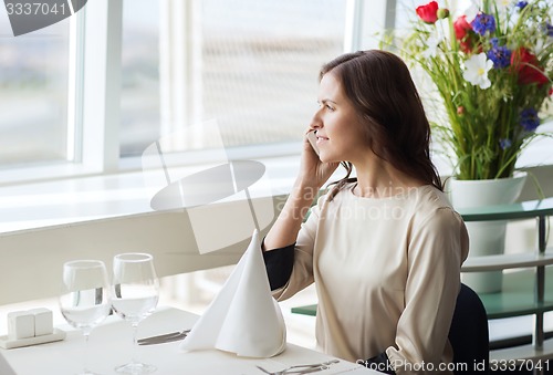 Image of happy woman calling on smart phone at restaurant