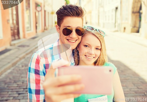 Image of smiling couple with smartphone in city