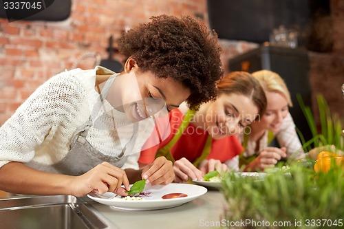 Image of happy women cooking and decorating dishes