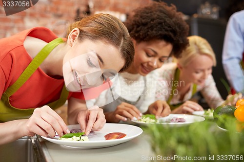 Image of happy women cooking and decorating dishes