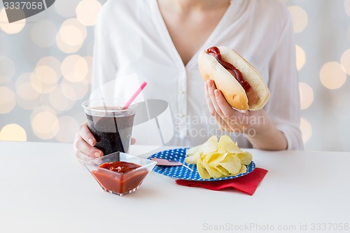 Image of close up of woman eating hot dog with cola
