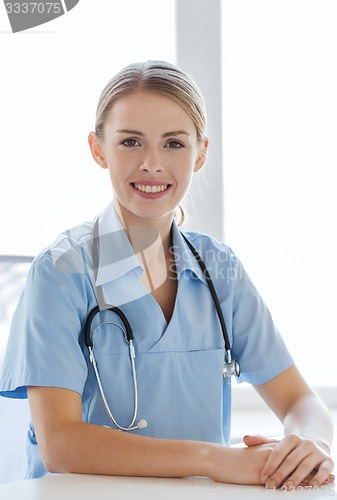 Image of happy doctor or nurse with clipboard at hospital