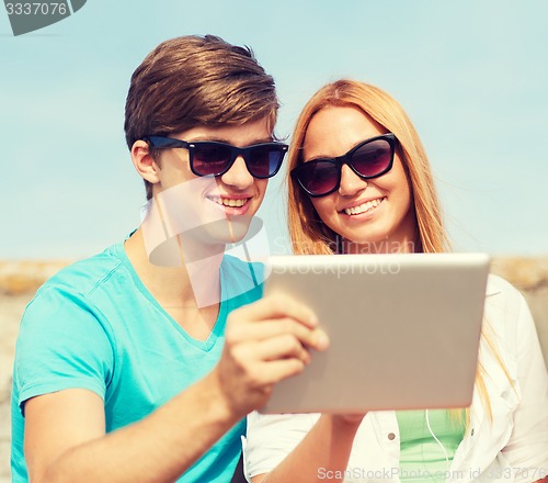 Image of group of smiling friends with tablet pc outdoors