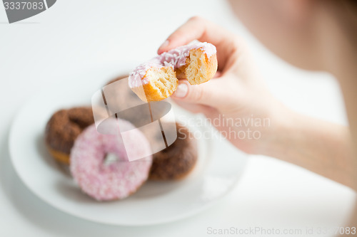 Image of close up of hand holding bitten glazed donut