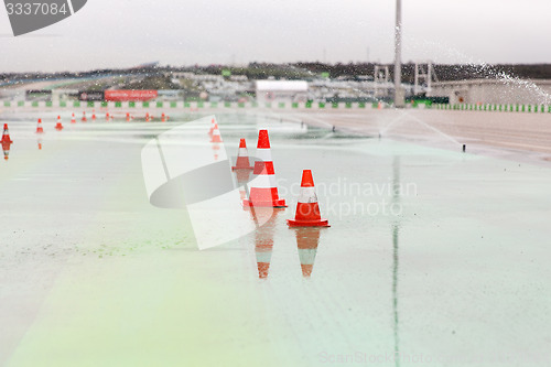 Image of traffic cones and sprinklers on wet speedway