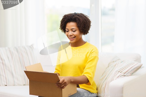 Image of happy african young woman with parcel box at home