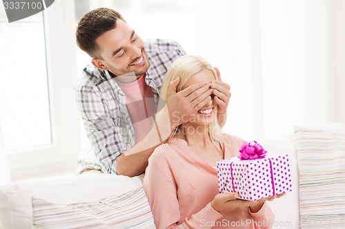 Image of happy man giving woman gift box at home