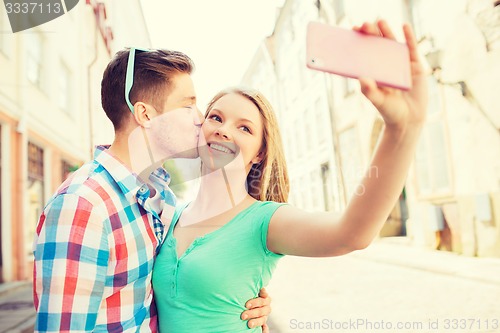 Image of smiling couple with smartphone in city