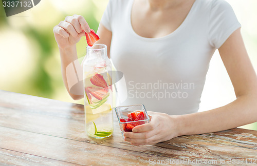 Image of close up of woman with fruit water in glass bottle