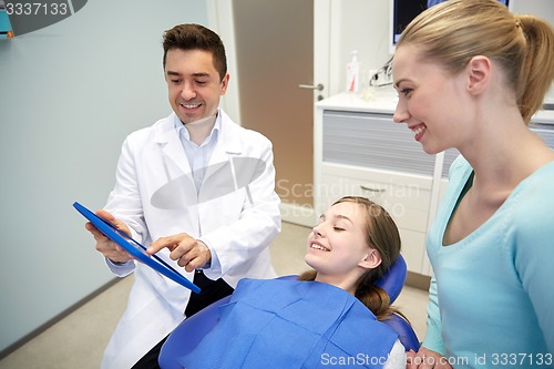 Image of dentist showing tablet pc to girl and her mother