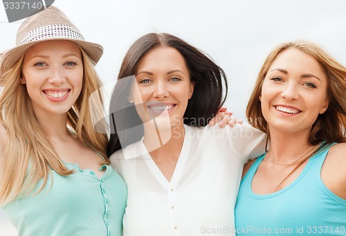 Image of group of smiling girls chilling on the beach