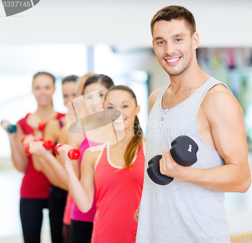 Image of group of smiling people with dumbbells in the gym