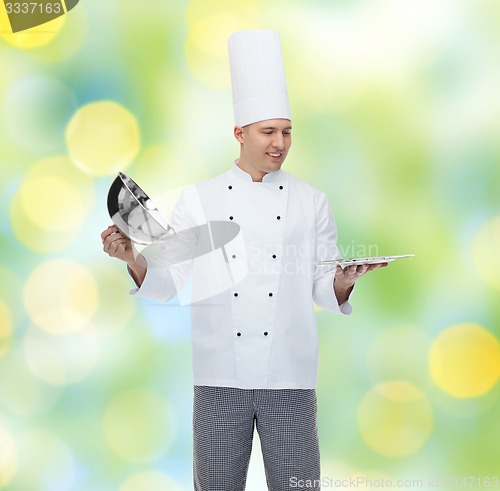 Image of happy male chef cook opening cloche