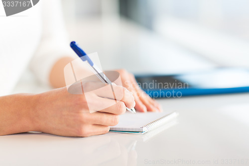 Image of close up of hands with pen writing to notepad