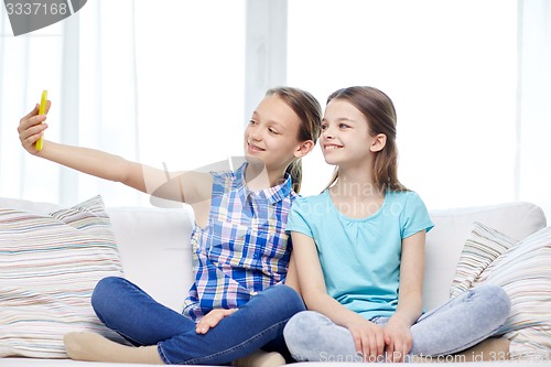 Image of happy girls with smartphone taking selfie at home