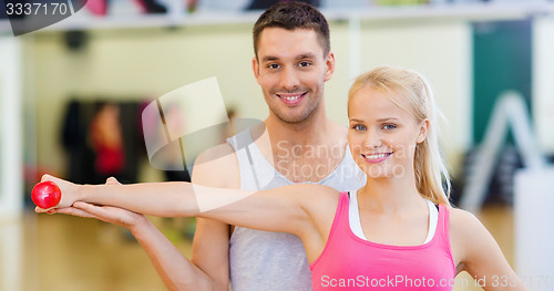 Image of male trainer with woman working out with dumbbell