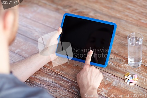 Image of close up of hands with tablet pc, pills and water