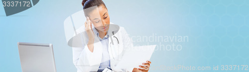 Image of female doctor with laptop pc looking at paper