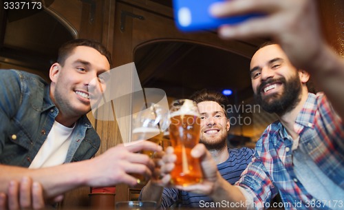Image of male friends with smartphone drinking beer at bar