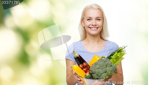 Image of smiling young woman with vegetables over green
