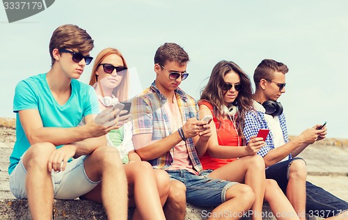 Image of group of friends with smartphones outdoors