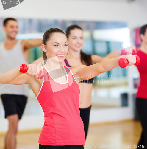 Image of group of smiling people working out with dumbbells