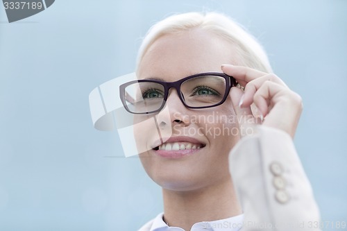 Image of young smiling businesswoman over office building