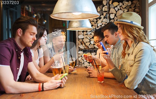Image of friends with smartphones and drinks at bar