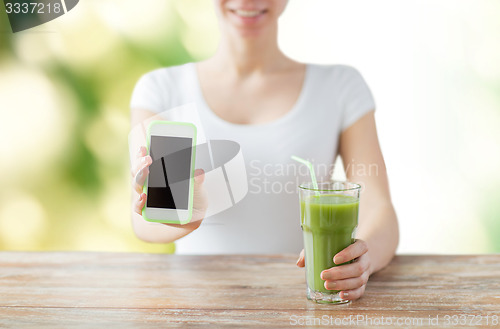 Image of close up of woman with smartphone and green juice