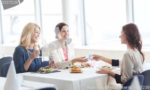 Image of happy women giving birthday present at restaurant