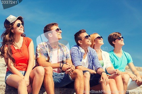 Image of group of smiling friends sitting on city street