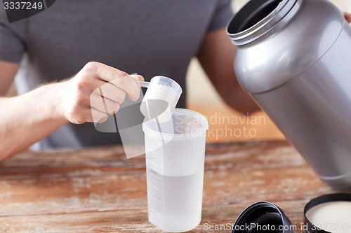 Image of close up of man with protein shake bottle and jar