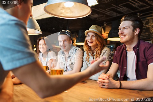 Image of happy friends drinking beer and talking at bar