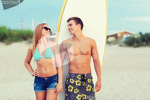 Image of smiling couple in sunglasses with surfs on beach