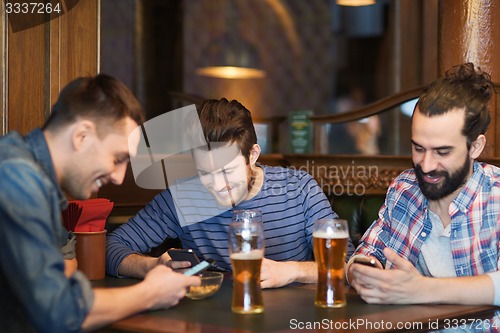 Image of male friends with smartphones drinking beer at bar