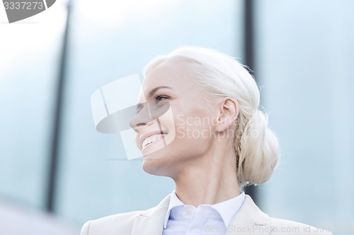 Image of young smiling businesswoman over office building