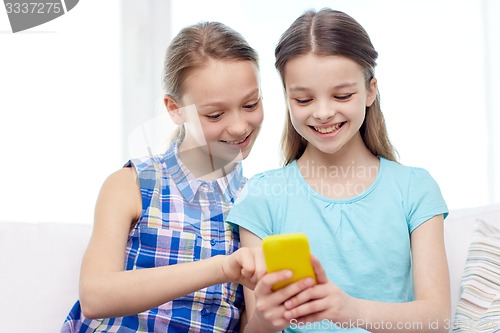 Image of happy girls with smartphone sitting on sofa