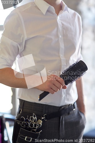 Image of close up of male stylist with brush at salon